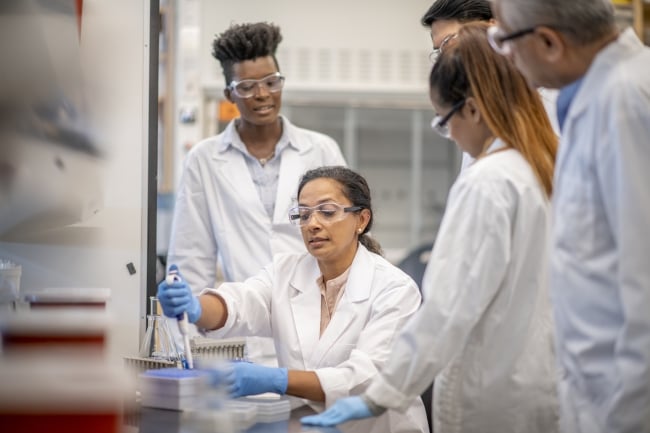 Woman showing chemistry students in a lab how to use a piece of equipment