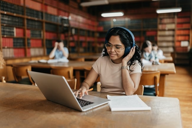 Female Indian student working on a laptop in a university library