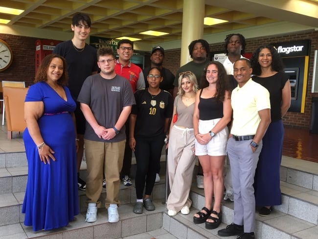 A group of students and staff members smile for a photo