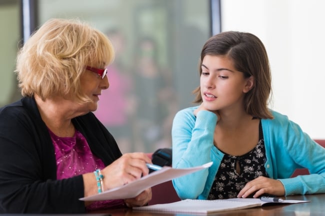 An older woman holding a piece of paper and a young woman looking at it