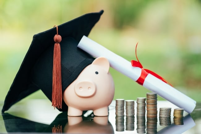 Piggy bank with graduation cap on black glass floor