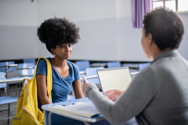 Teenaged student talking with a staff member in the classroom