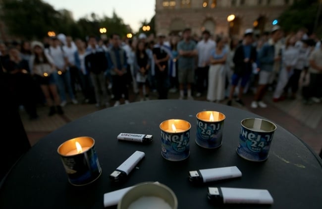 Candles and lighters are seen in the foreground while individuals stand in the background.