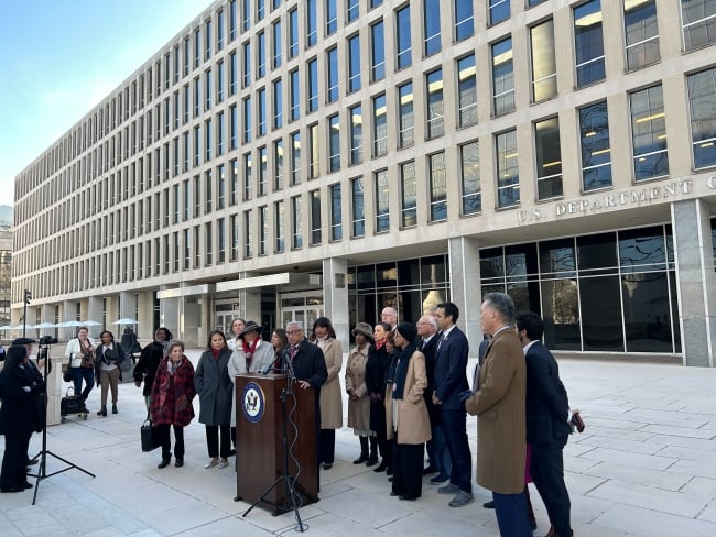 Lawmakers stand at a podium outside the Education Department building