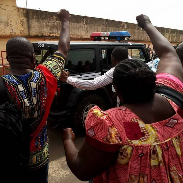 Supporters of Patrice Nganang are shown outside a police vehicle.