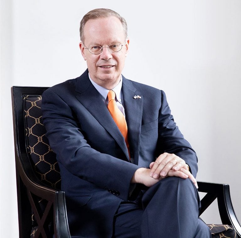 Kent Syverud, a white man with sandy hair wearing glasses and a business suit, with a tie in Syracuse orange.