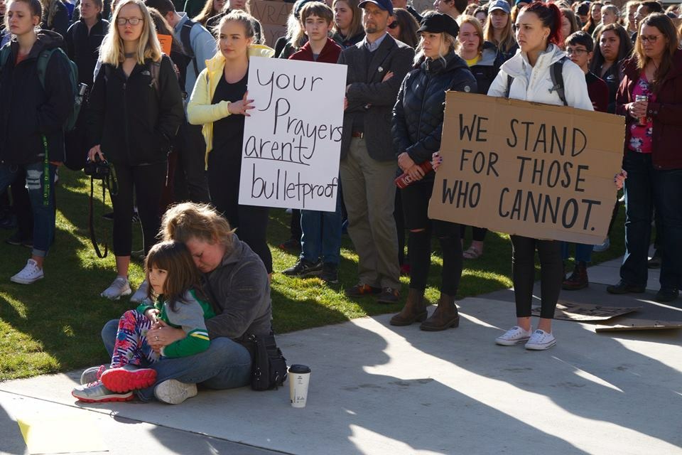 University of Oregon students at a protest against gun violence hold signs saying "Your prayers aren't bulletproof" and "We stand for those who cannot."