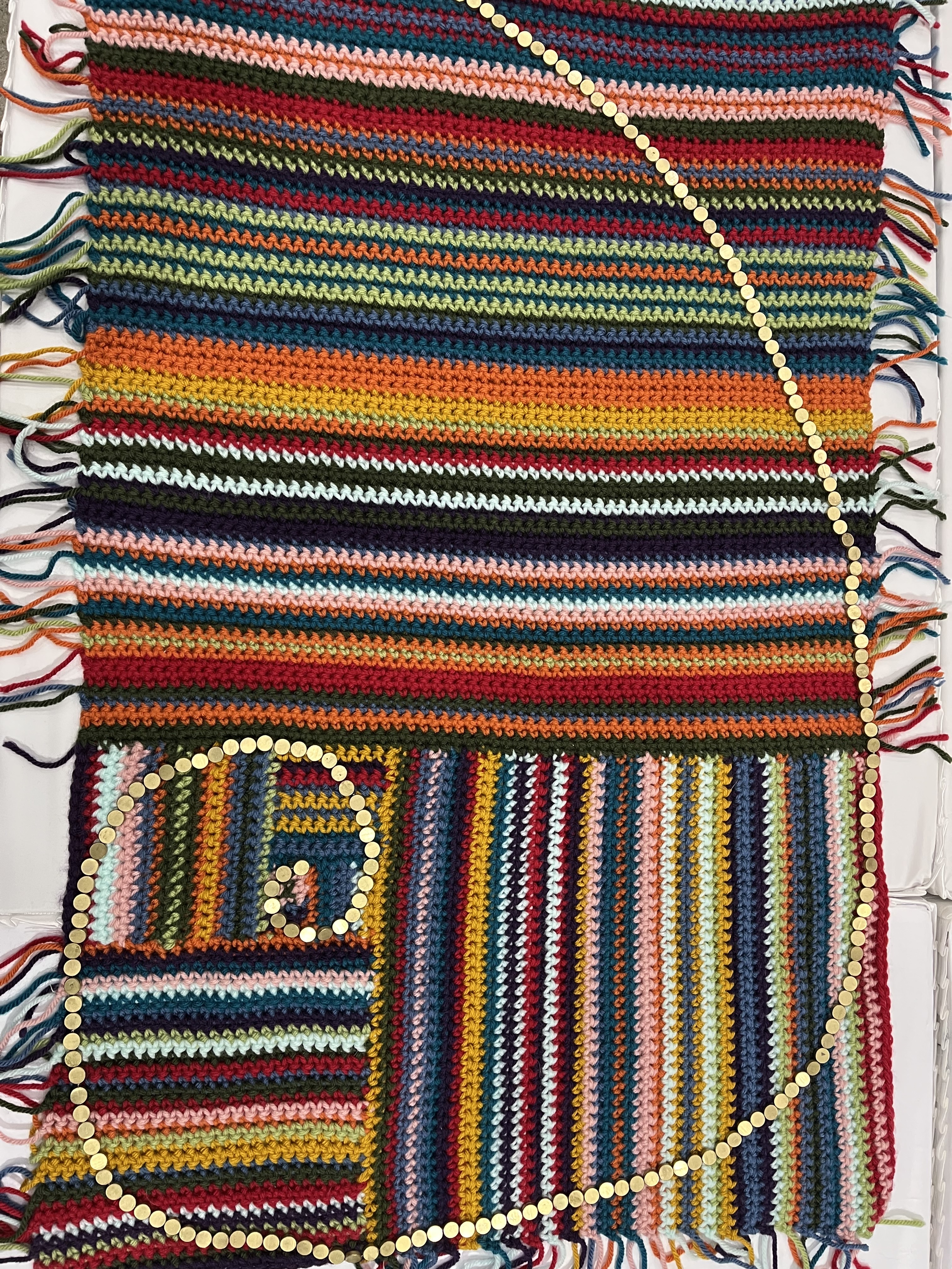 A rectangular, multicolor, crocheted piece of mathematical art representing the golden ratio, the dimensions of squares making up the rectangle flow the Fibonacchi sequence. By Dennis Bromley, Samantha Pezzimenti and Marina Skyers at the University of Kentuckey Math Lab. Displayed at the 2023 Joint Math Meetings.  