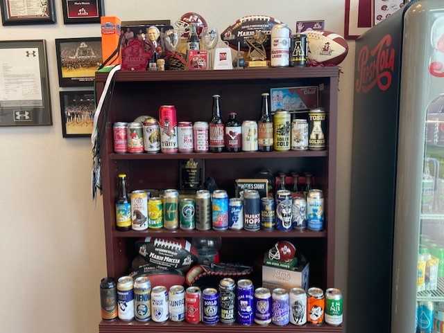 Mario Moccia's collection of collegiate-branded cans, arranged in color order.